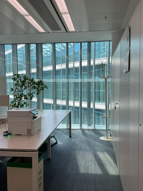 Des laveurs de vitres en hauteur, équipés de protections, nettoient la façade d’un gratte-ciel.